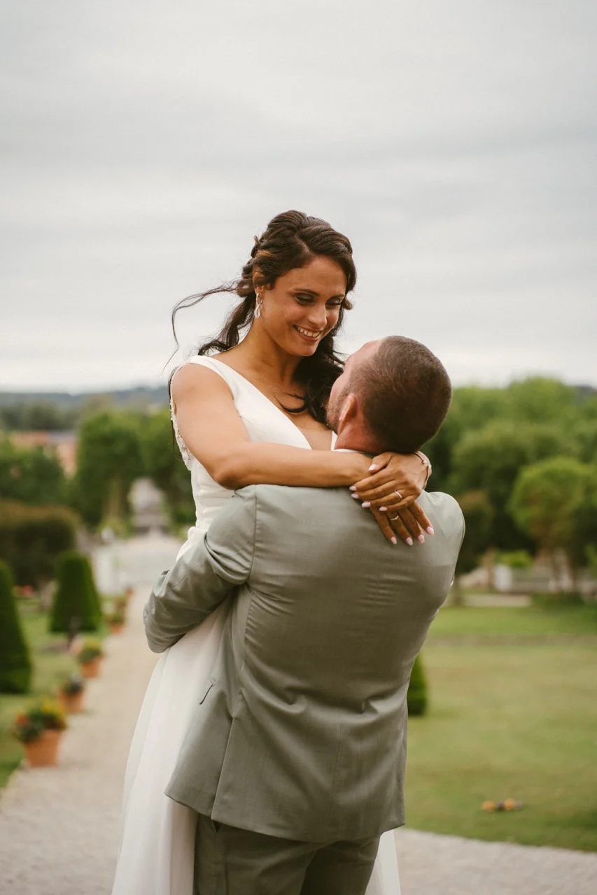 Une mariée enlace son époux dans les jardins