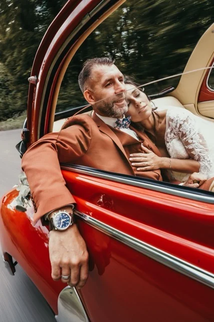 Le marié en costume terracotta près de sa voiture ancienne