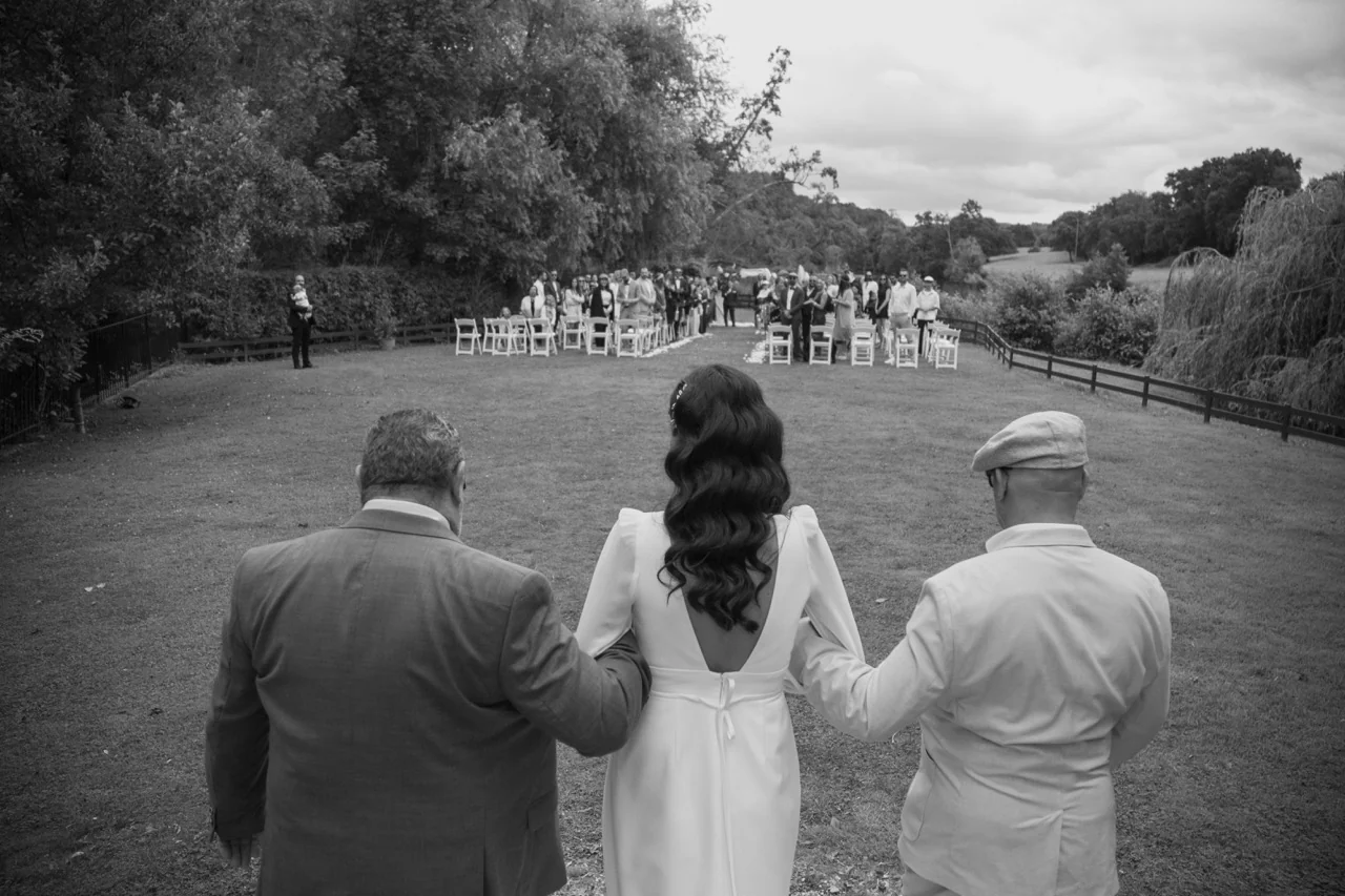 La mariée avance vers la cérémonie au bras de ses proches