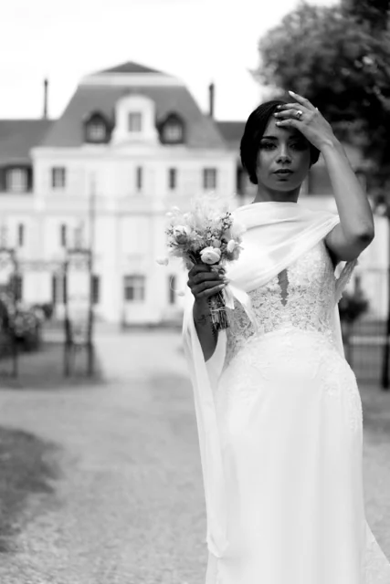 Une mariée souriante devant le château, photographiée en noir et blanc