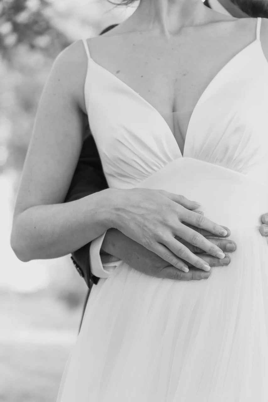 Détail en noir et blanc de la robe et des mains de la mariée