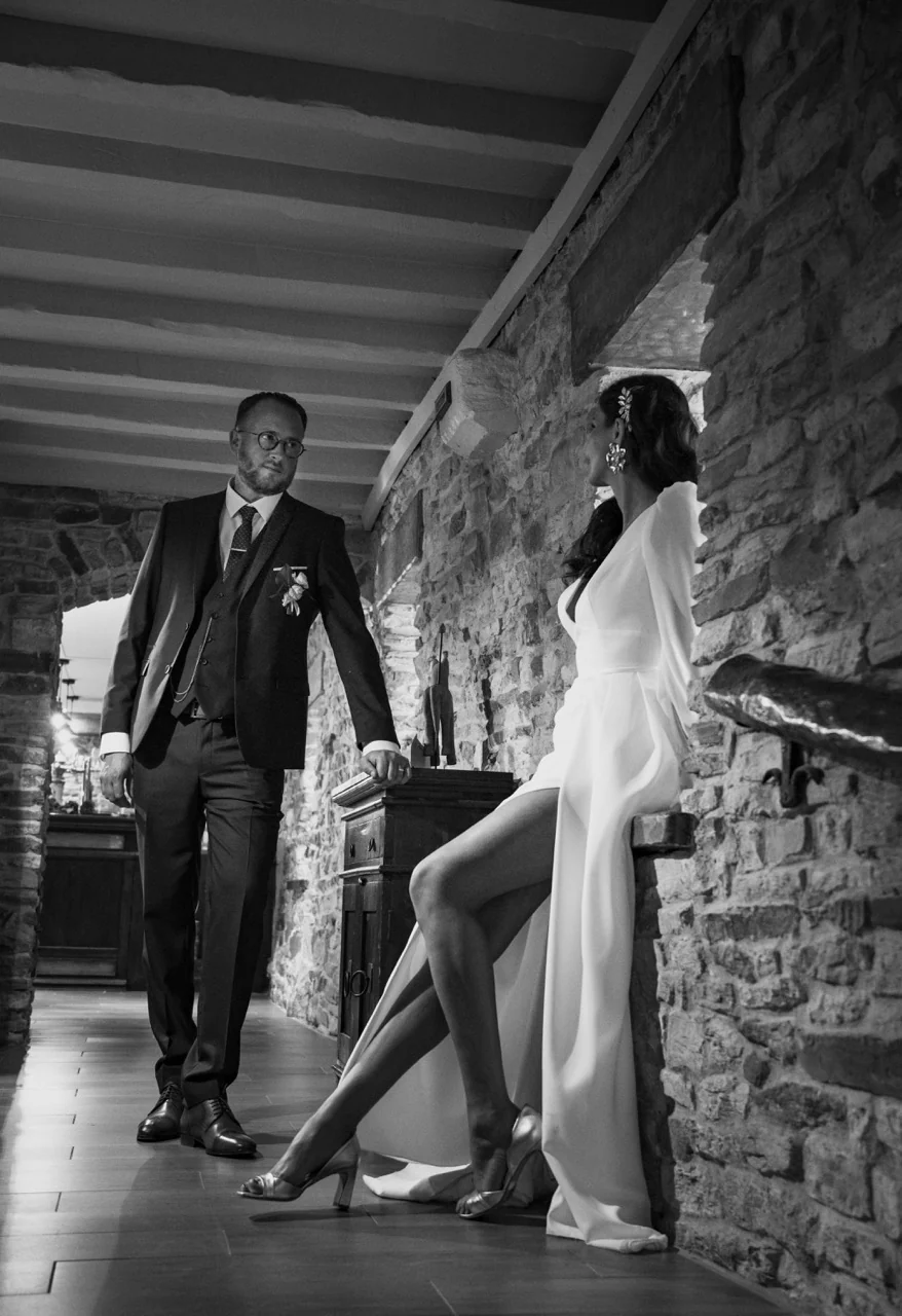 Un couple de mariés sous une galerie de pierre, en noir et blanc