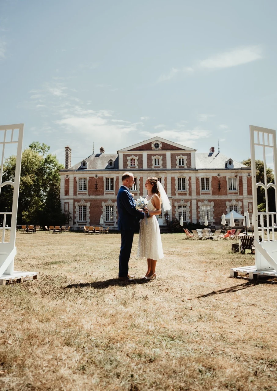 Un couple de mariés devant les grilles d’un château
