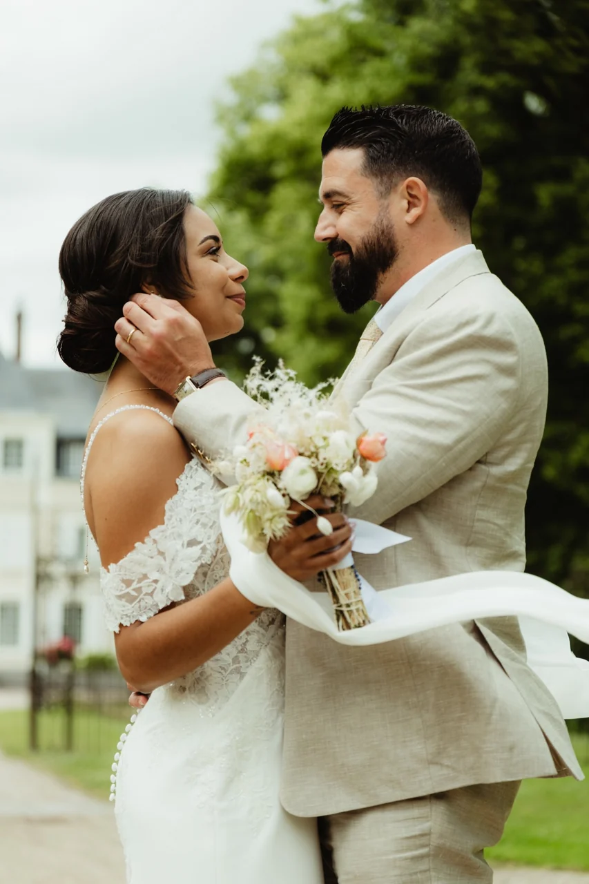 Un couple de mariés s’embrasse dans les jardins