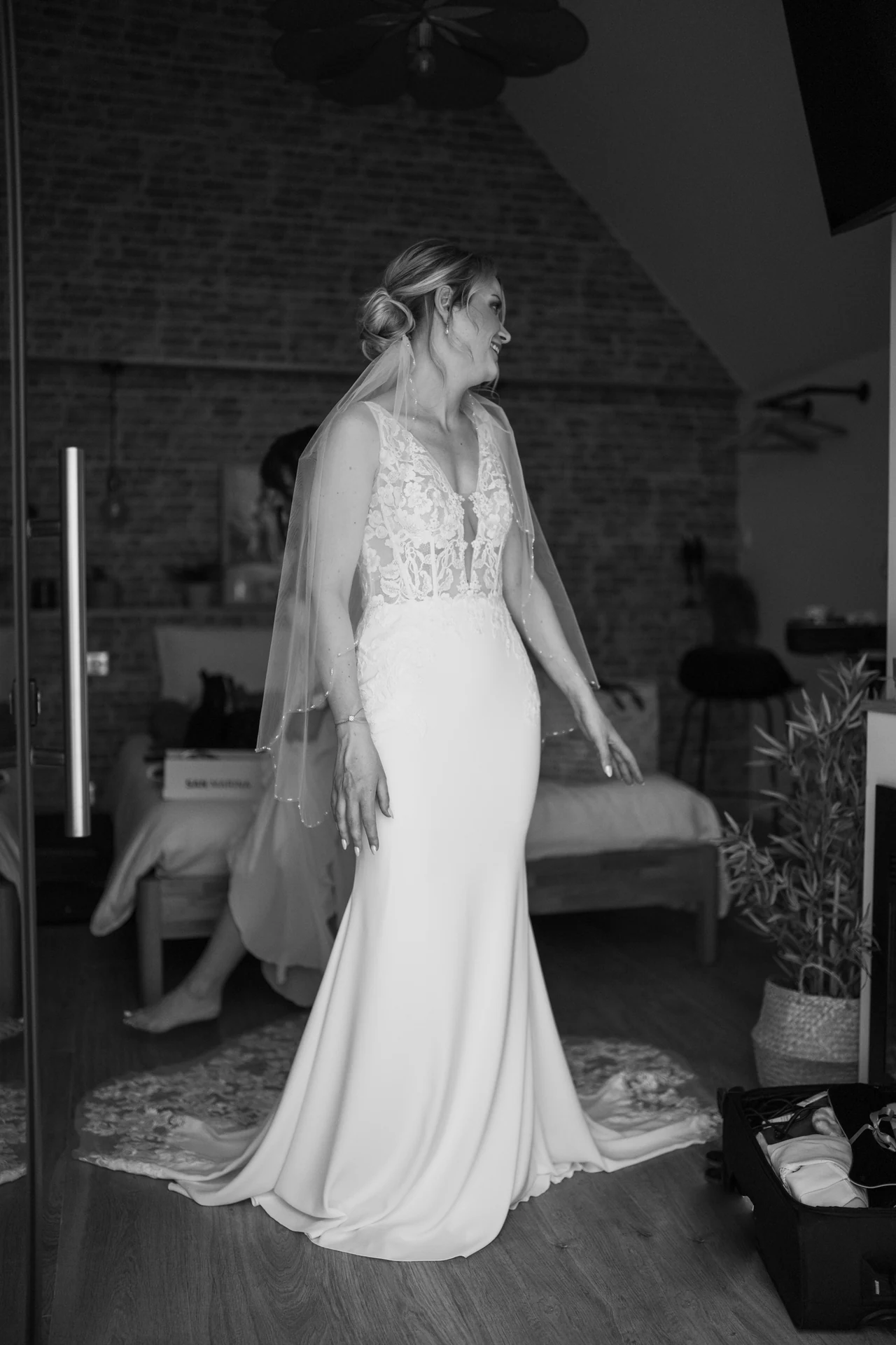 La mariée sourit pendant les préparatifs, en noir et blanc